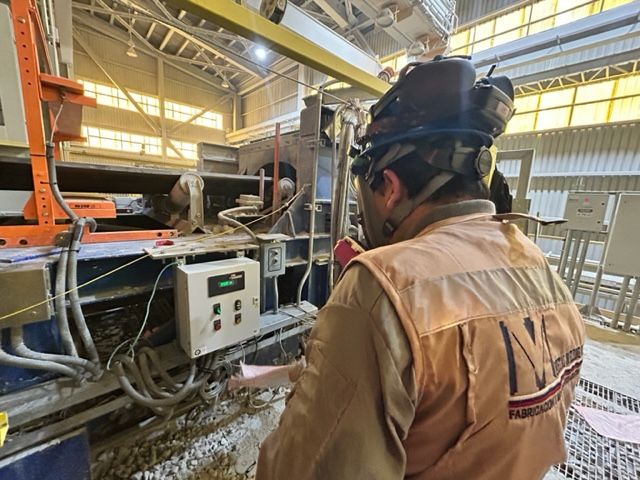 Técnico de Metal Welding Varas en faena minera junto a panel de control de correa